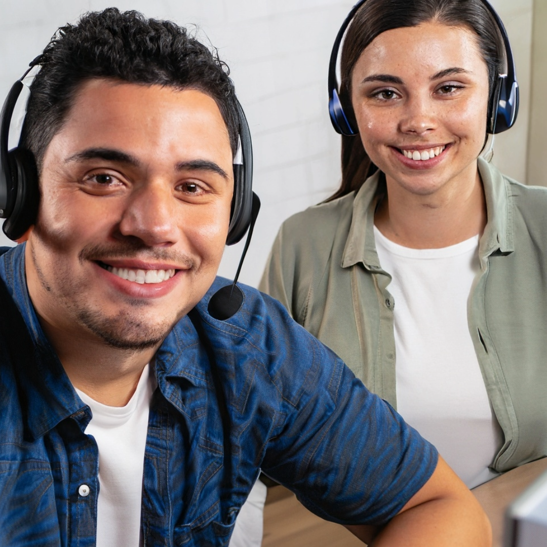 Homem e mulher usando headsets sorriem para a câmera